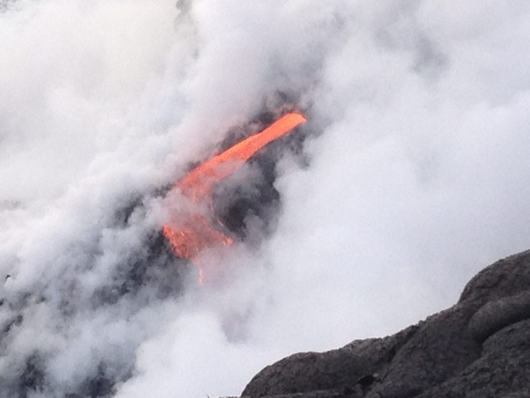 A lava stream disappearing into thick white steam