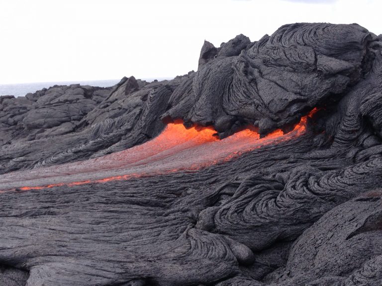 A thin orange line of lava along the edge of a grey flow