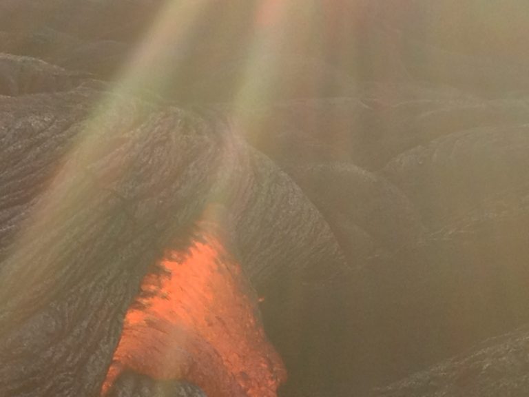 Sun rays over a lava field with a glowing breakout below