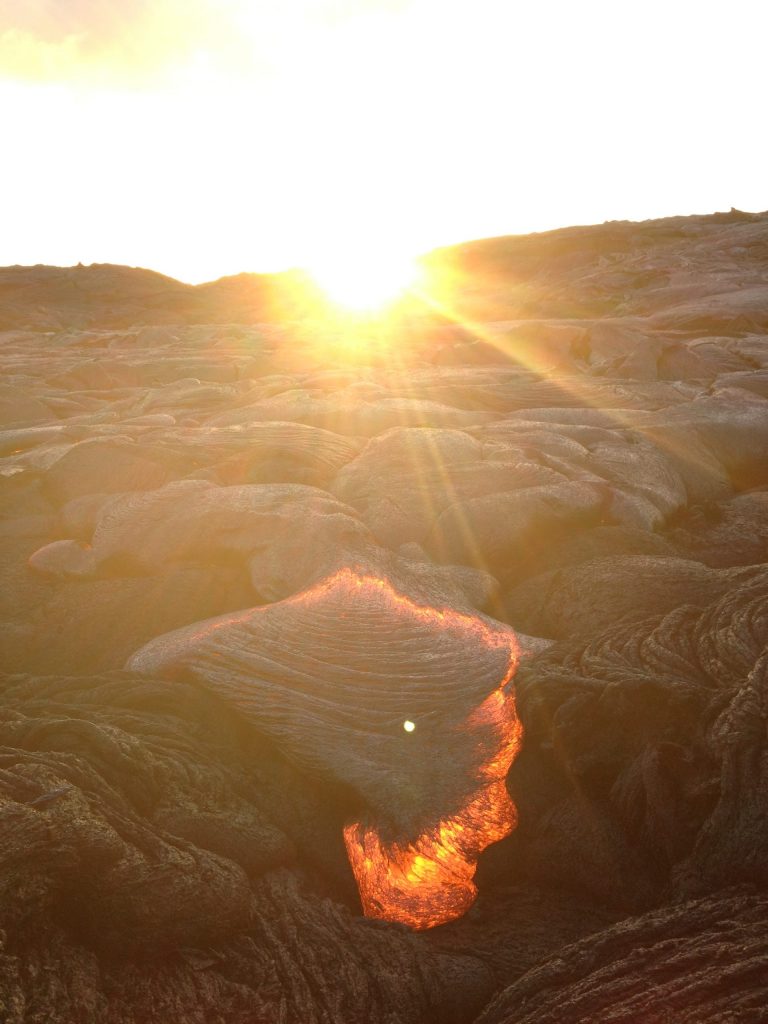 The sun setting behind a small lava breakout on a rough flow