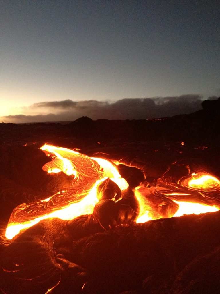 Bright lava channels on a dark lava field at dusk