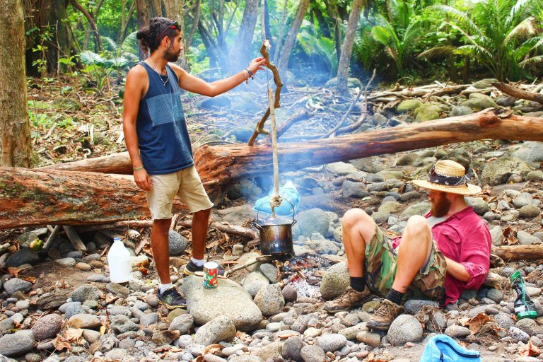 Two hikers boiling water at a campsite in the forest