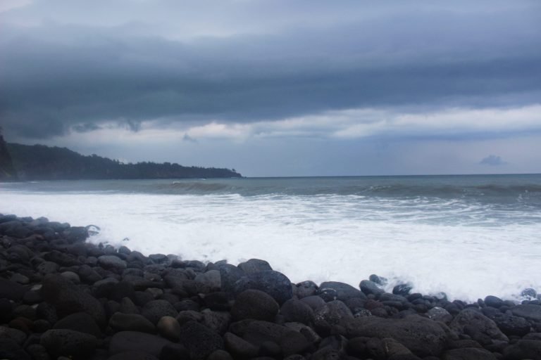 Dark storm clouds over waves breaking on a boulder shore