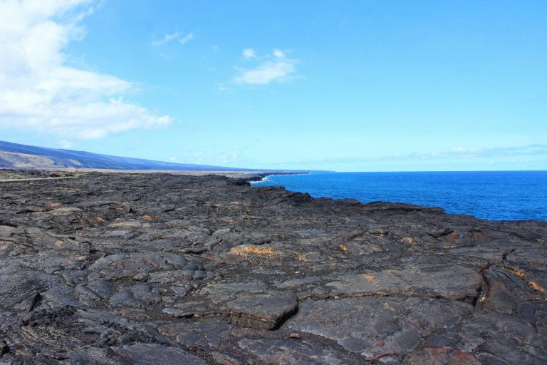 Black lava rock ending at a deep blue ocean