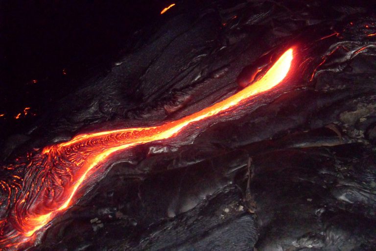A glowing ribbon of lava winding over black rock