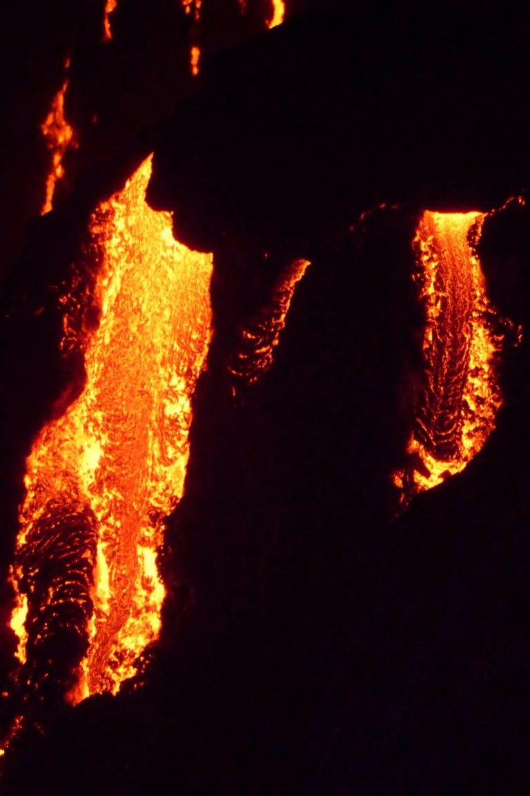 Lava spilling in bright streams down a dark face